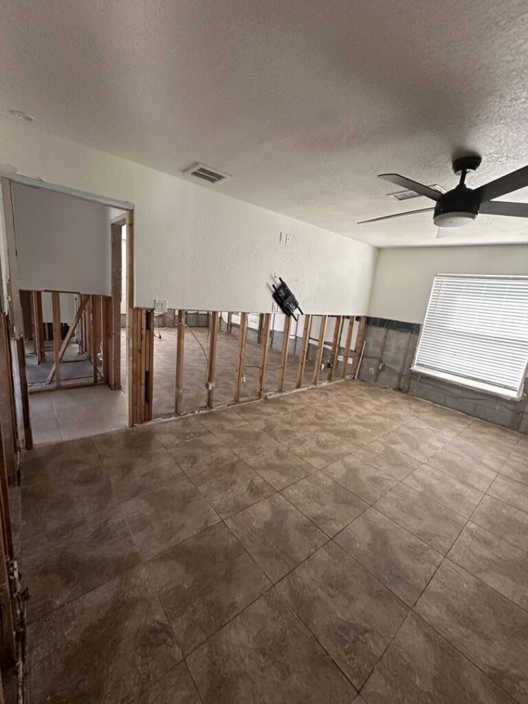 A room with lower drywall removed, exposing studs and concrete blocks during water damage remediation by Catalyst Restoration in Hagerstown, MD.