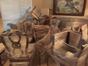 A room filled with various pieces of furniture, professionally wrapped in plastic and ready for moving by Kingdom Men Movers in Houston, TX.