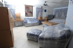 A room with furniture wrapped in plastic and moving boxes, prepared by Moving Pros LLC in Surprise, AZ.