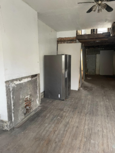 Room interior demolition with a partially removed fireplace and exposed floorboards by Identical Demolition LLC in Philadelphia, PA.