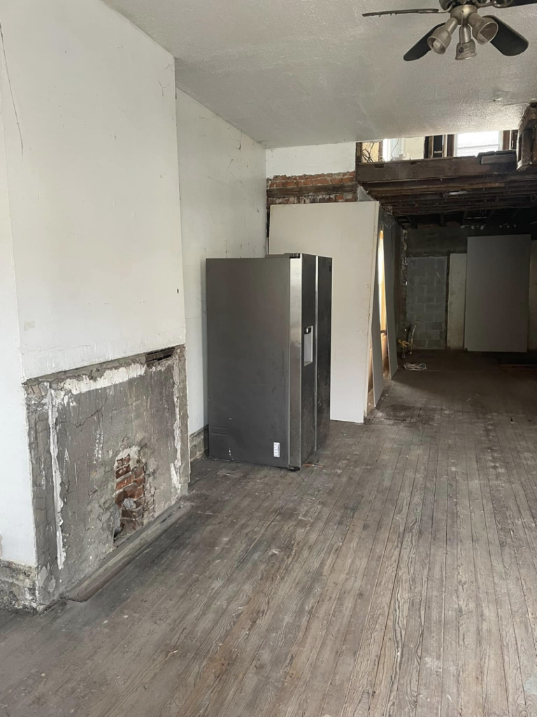 Room interior demolition with a partially removed fireplace and exposed floorboards by Identical Demolition LLC in Philadelphia, PA.