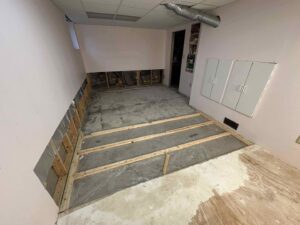 A room undergoing water damage demolition with exposed concrete floor and wall studs by RestoPros of Eastern & Central Maine in Bangor, ME.