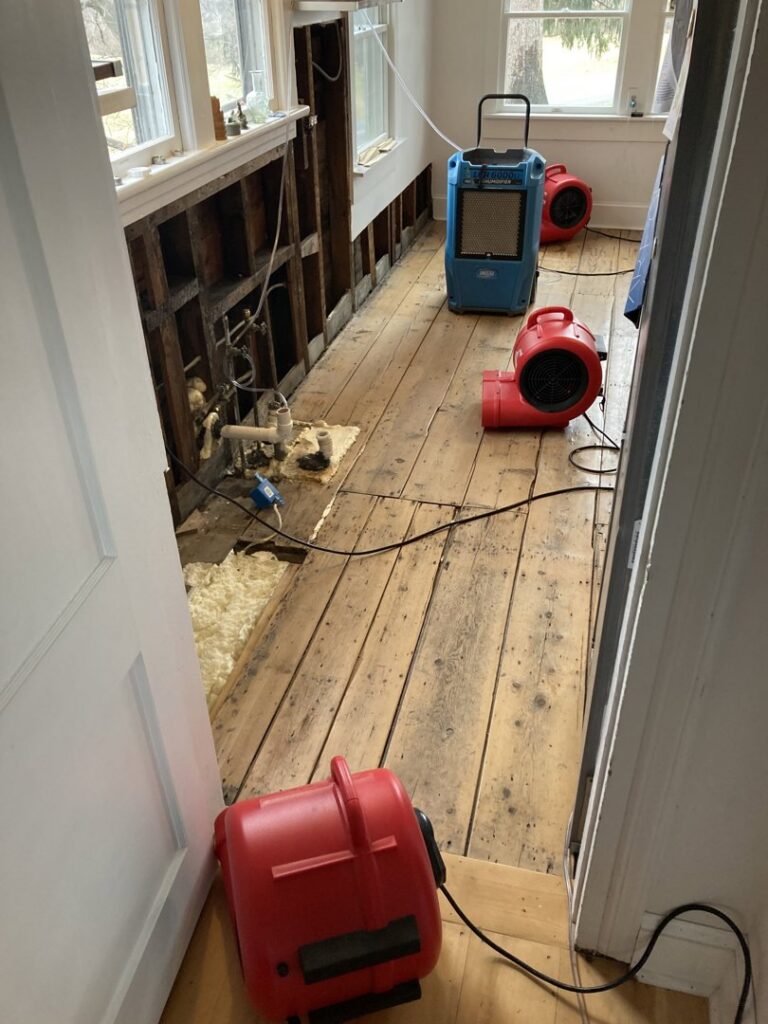 A room undergoing water damage remediation and drying with exposed studs and equipment by CleanBright Surface Restoration in Latham, NY.