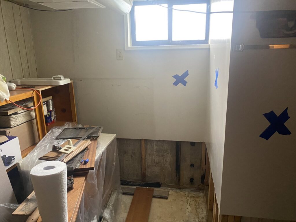 A room undergoing water damage repair with walls removed and exposed studs marked with blue tape by ServiceMaster of Salt Lake in Salt Lake City, UT