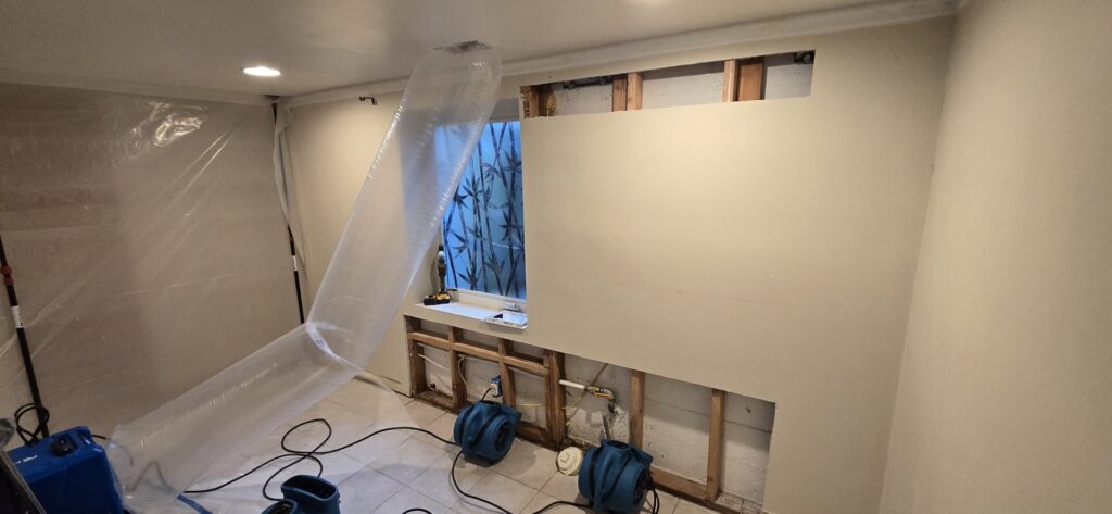 A room with plastic containment and air movers for water damage drying by Harbaugh Restoration in Vancouver, WA.