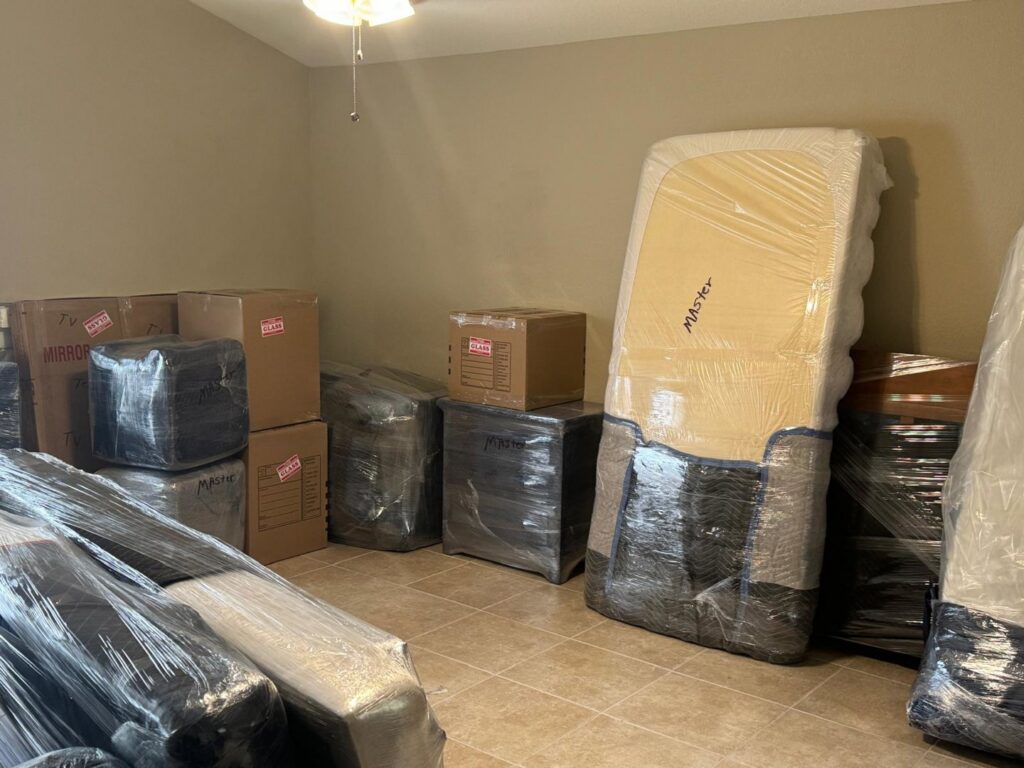 A room filled with wrapped furniture and boxes, prepared for moving by Household Goods Moving and Storage in Rockville, MD