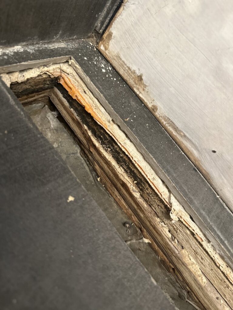 Close-up of rotted wood flooring and subfloor showing severe water damage and discoloration, requiring expert repair from Standard Restoration in Salt Lake City, UT.