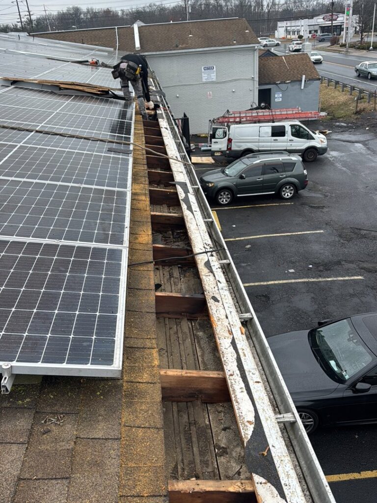 A worker repairing a gutter system with visible rotted wood, a clear sign of water damage, by Homcertin llc in Trenton, NJ.