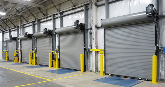 A row of commercial rolling garage doors inside an industrial building by Vertical Door Solutions in Sheridan, WY