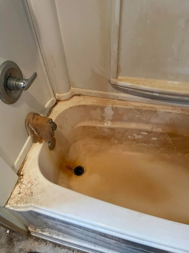 A heavily rust-stained bathtub before deep cleaning services by Teri Lynn's Cleaning in Williston, ND.