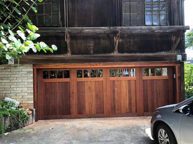 A newly installed rustic wood panel garage door with windows by Oahu Garage Doors in Waipahu, HI