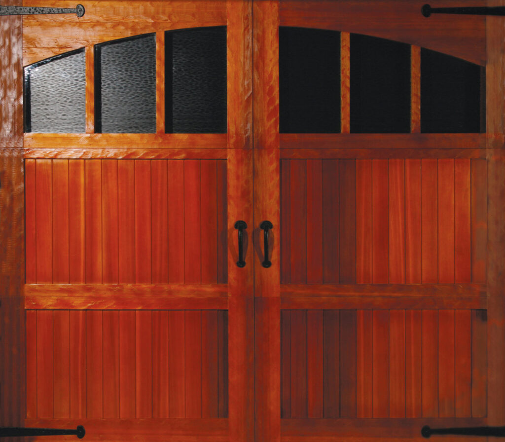 A rustic wooden garage door with arched windows and decorative hardware installed by Overhead Door of Sierra Nevada in Reno, NV.