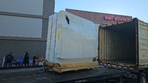 A large yellow RV or motorhome being transported on a flatbed tow truck by AB Towing & Transport in San Antonio, TX.