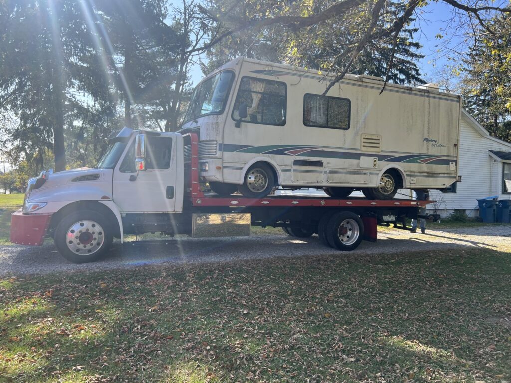 A large RV or motorhome being towed on a flatbed tow truck by Quiñones Towing in Cleveland, OH.