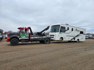 A large RV being towed by a heavy-duty wrecker from Gem State Towing and Recovery in Caldwell, ID.