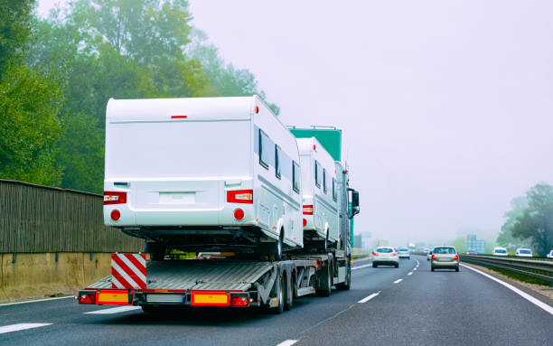 A large truck transporting two RVs on a flatbed trailer for San Diego Alpha Towing in San Diego, CA