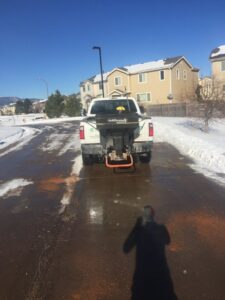 A pickup truck with a SaltDogg spreader from TLC Lawn Care and Snow Removal LLC de-icing a road in Colorado Springs, CO.