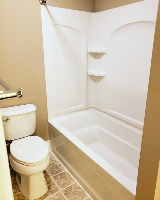 A sanitized bathroom featuring a white toilet and a clean bathtub and shower combo, cleaned by A To Zen in Lansing, MI.