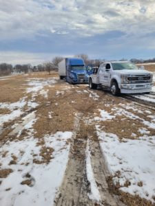A tow truck recovering a semi-truck from a snowy field for Diversified Towing and Recovery, LLC in Creston, IA.