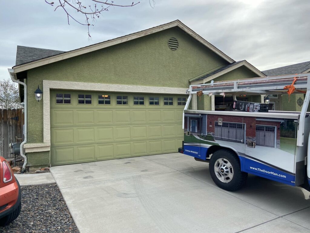 The Door Man - Garage Doors & Openers service truck parked at a residential job site with a green garage door in Reno, NV