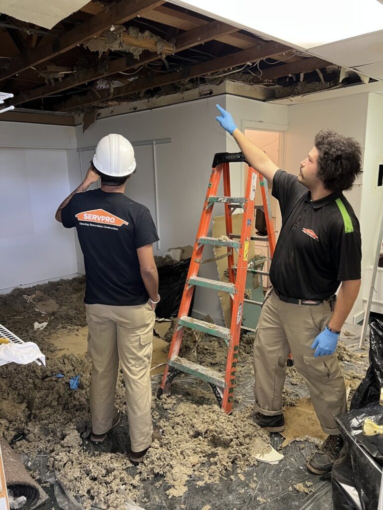 Servpro crew inspecting severe ceiling water damage and debris in a room in Athens, AL, ready for restoration.
