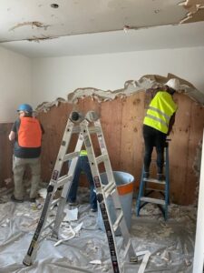 A Servpro of Bend crew removing water-damaged drywall and insulation from a wall in Bend, OR