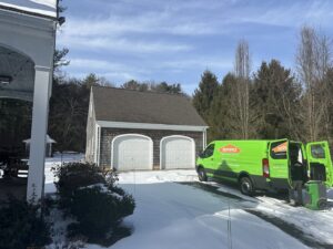 A Servpro crew unloading water damage restoration equipment from a van in a snowy driveway, ready for a job in New Bedford, MA