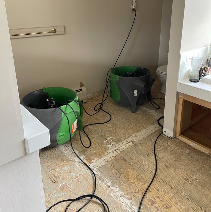 SERVPRO of Barre, Montpelier drying equipment operating in a water-damaged bathroom with exposed subfloor in Barre, VT.