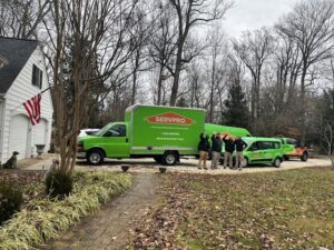 A SERVPRO team and their branded vehicles parked outside a residential home, ready for restoration services in Annapolis/Severna Park, MD.