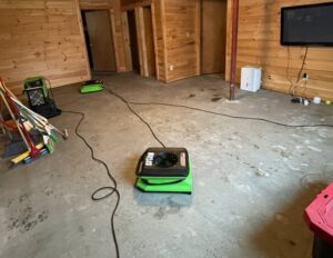 Servpro Team Paul water damage specialists drying a basement floor with multiple green drying units in Montpelier, VT.