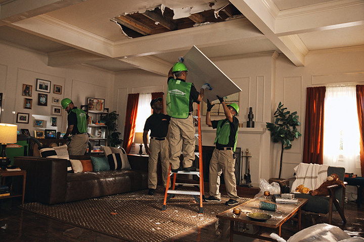 Servpro team repairing a damaged ceiling in a living room after water damage in Athens, AL.