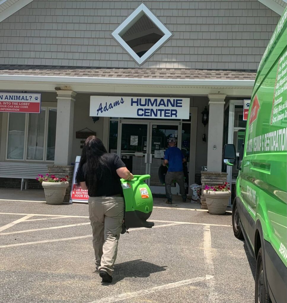 A Servpro technician carrying an air mover into a building for water damage restoration in Athens, GA.