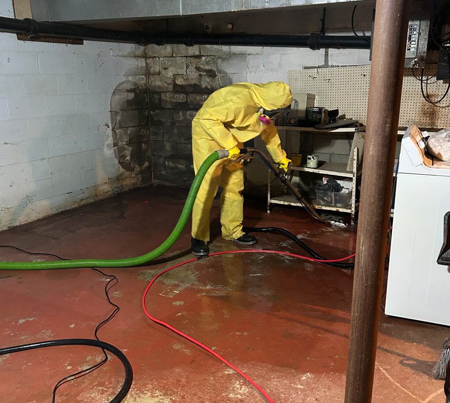 A SERVPRO of Barre, Montpelier technician in a hazmat suit cleaning a water-damaged basement floor in Barre, VT.