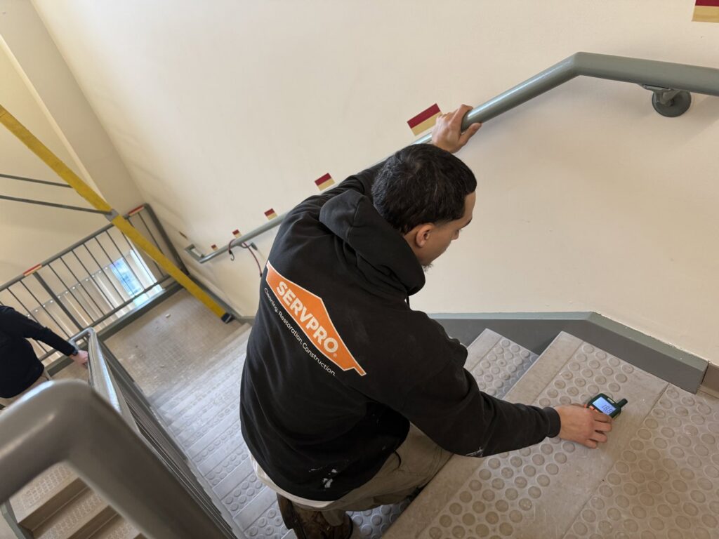 A Servpro technician using a moisture meter to assess water damage on a staircase in New Bedford, MA