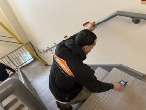 A Servpro technician using a moisture meter to assess water damage on a staircase in New Bedford, MA