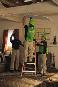 Servpro of Bend technicians removing a water-damaged ceiling panel in a home in Bend, OR