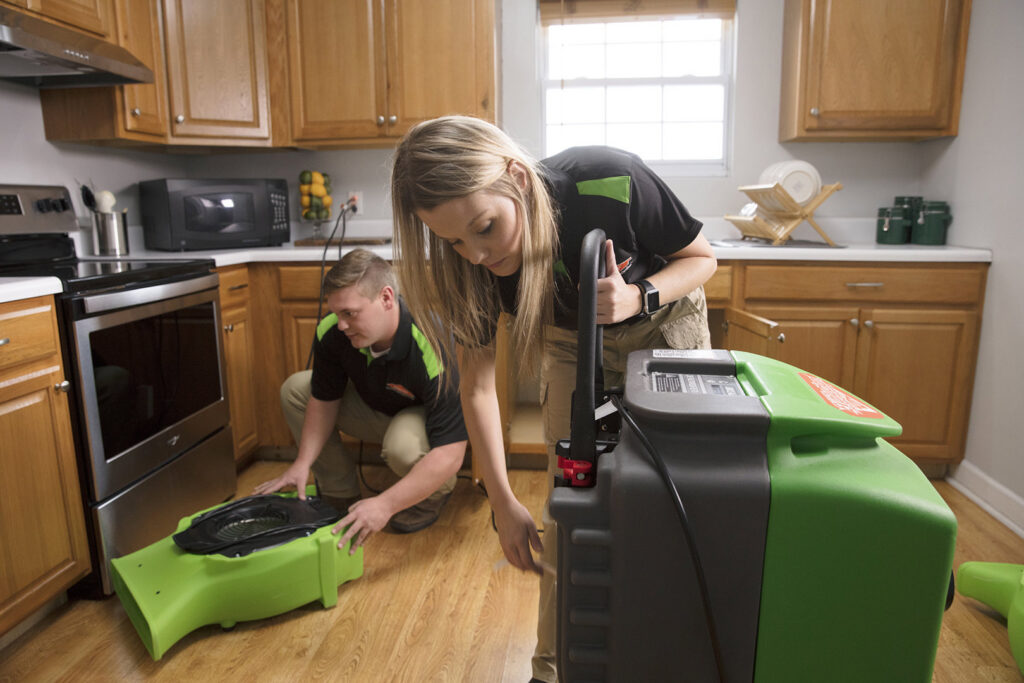 SERVPRO technicians setting up professional drying equipment in a kitchen after water damage in Boise/Meridian, ID
