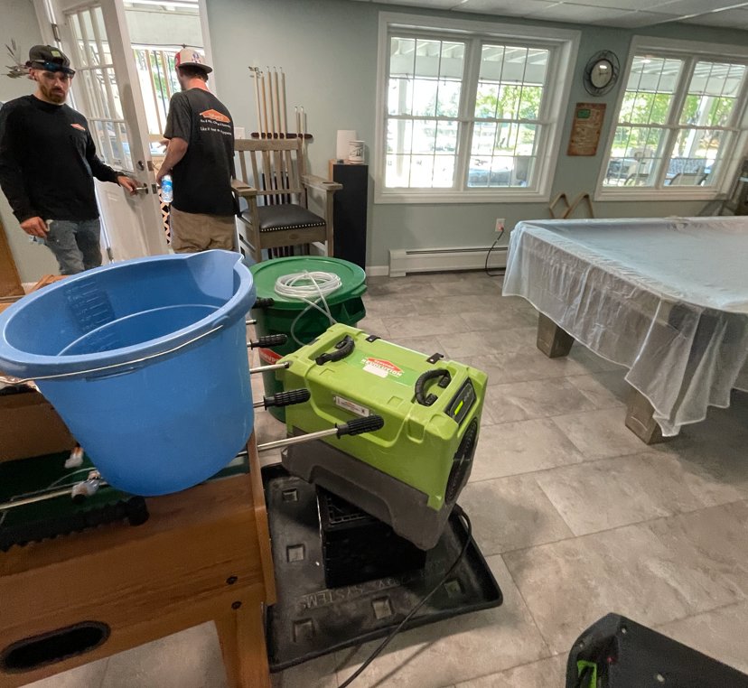 SERVPRO of Barre, Montpelier technicians setting up water damage drying equipment in a recreational room in Barre, VT.
