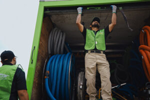 Servpro technicians unloading large water extraction hoses and equipment from a truck, preparing for a job in New Bedford, MA