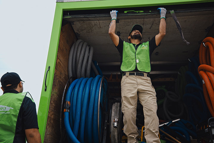Servpro technicians unloading large water extraction hoses and equipment from a truck, preparing for a job in New Bedford, MA