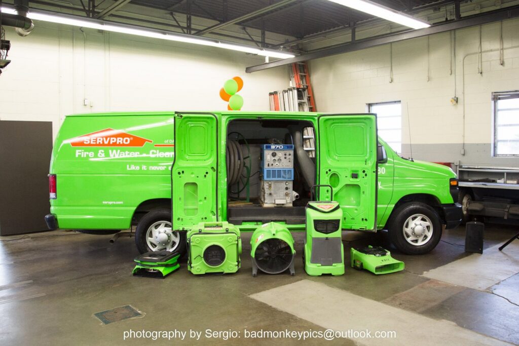 A Servpro van with its doors open, displaying various water damage restoration equipment like air movers and dehumidifiers, in New Bedford, MA