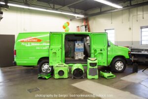 A Servpro van with its doors open, displaying various water damage restoration equipment like air movers and dehumidifiers, in New Bedford, MA