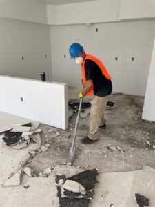 A Servpro of Bend worker shoveling water-damaged flooring debris during restoration in Bend, OR