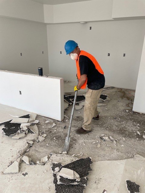 A Servpro of Bend worker shoveling water-damaged flooring debris during restoration in Bend, OR