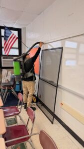 A Servpro worker using a backpack vacuum to clean a classroom wall for Servpro of SW Onondaga County in Syracuse, NY.