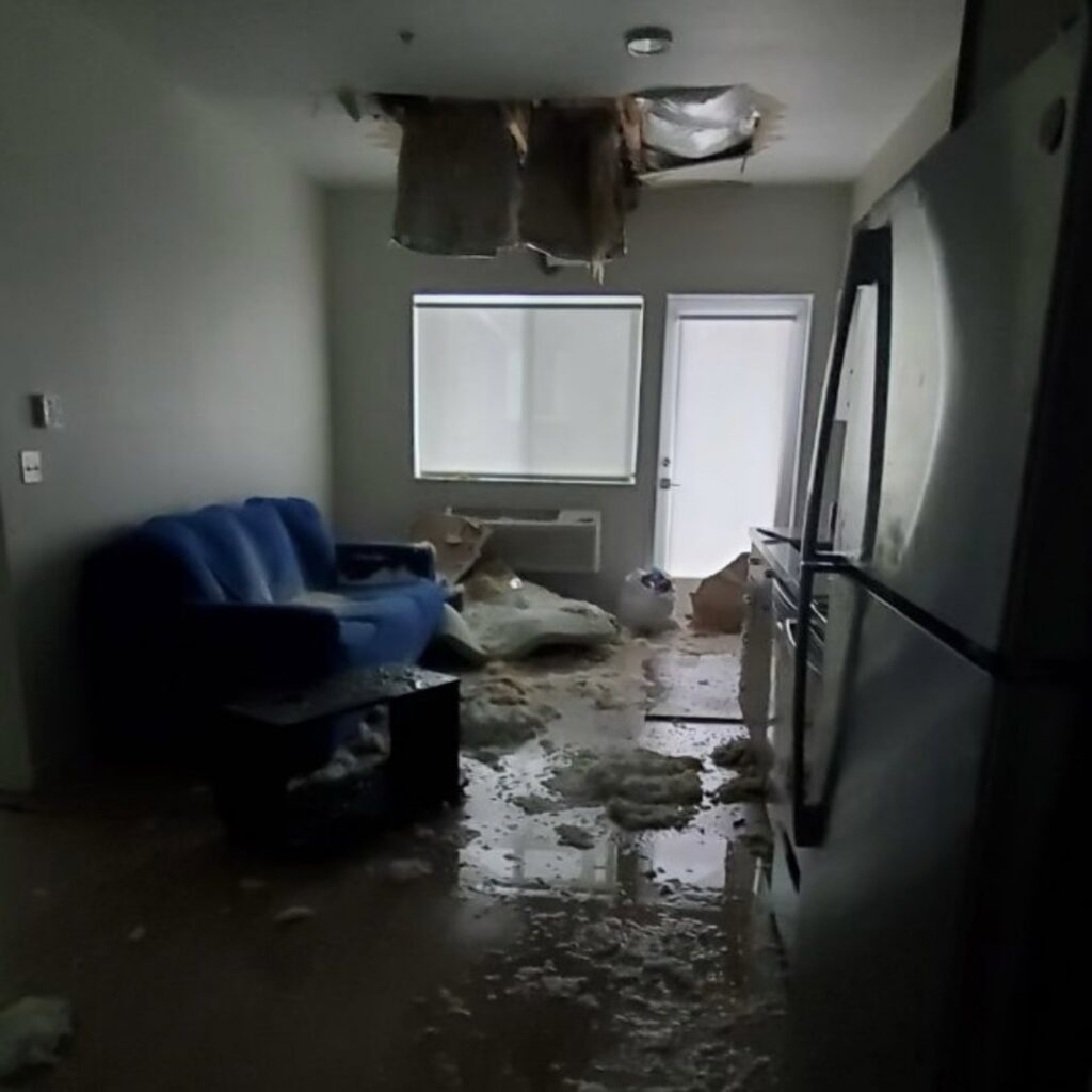 A severely water-damaged apartment with a collapsed ceiling and debris on the floor, requiring restoration by The Recover Tech Restoration in Vancouver, WA.