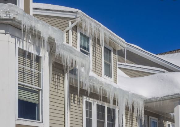 Severe icicles hanging from a house roofline, indicating ice damming and potential water damage, a service provided by Local Clean Up Specialists in Green Bay, WI.
