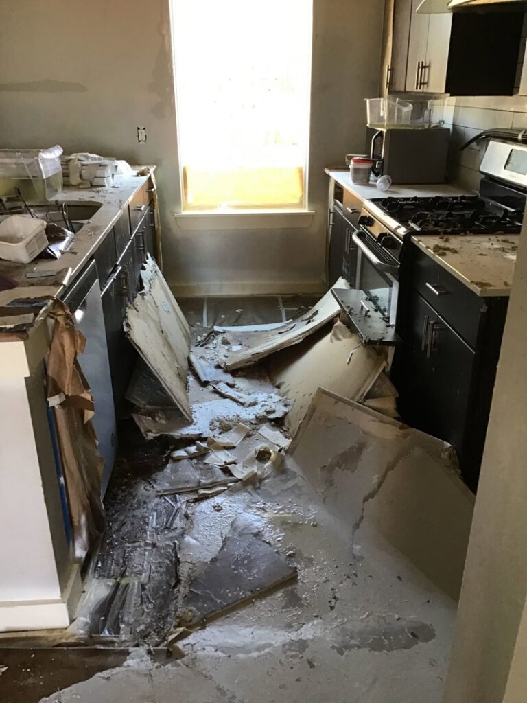 A severely damaged kitchen with debris and water on the floor, undergoing restoration by Service Professionals in Edmond, OK.