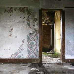 A severely water-damaged room with peeling wallpaper and stained floors, indicating the need for restoration services from Rainbow Restoration of the Capital Region in Clifton Park, NY