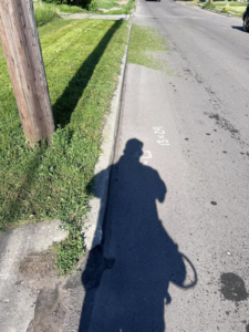 A shadow of a lawn care professional edging grass along a sidewalk for Vick's Lawn Care Service in Des Moines, IA.